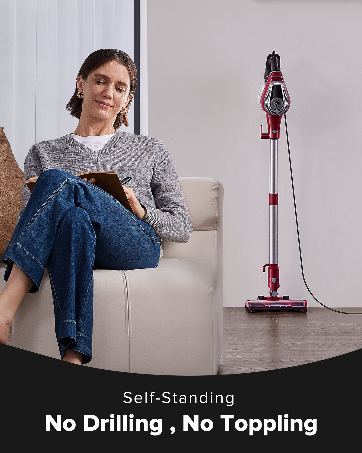 Woman sitting on a couch with a tablet next to a self-standing vacuum cleaner.