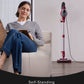 Woman sitting on a couch with a tablet next to a self-standing vacuum cleaner.