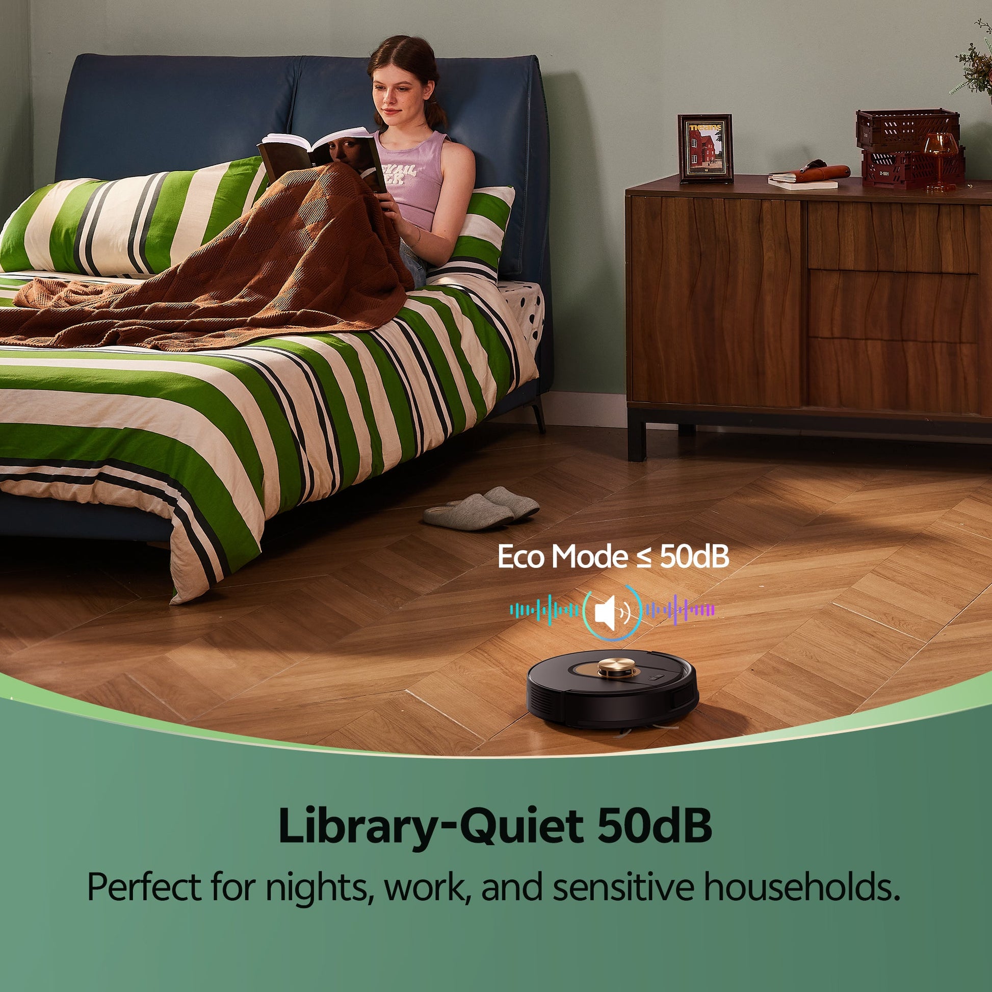 Woman reading in bed with a robot vacuum cleaner on the floor, emphasizing eco mode and noise level.